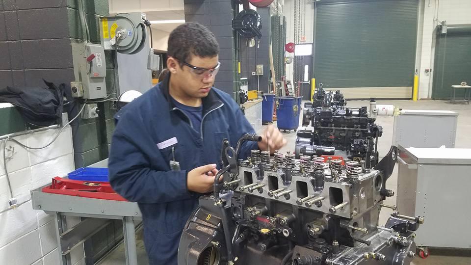 Picture of student removing push rods from the engine he is working on during the disassembling process.